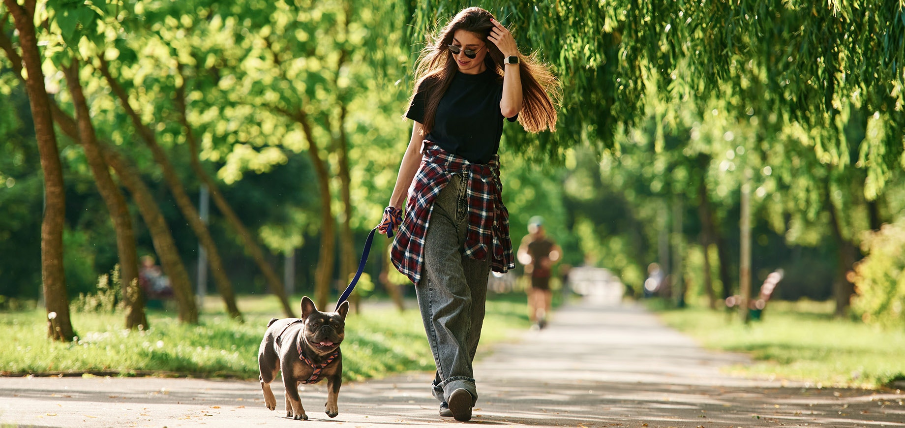 Frau geht mit ihrem Hund im Park spazieren.